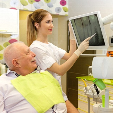 Older patient smiling with an implant dentist in Guilderland