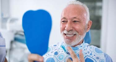 senior man admiring his new dental implants in Guilderland