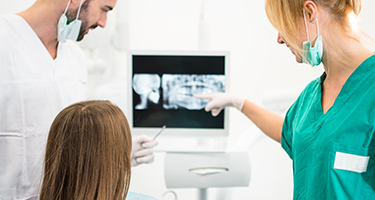 Dentist team member and patient looking at dental x-rays