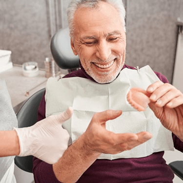a patient smiling after receiving his new dentures