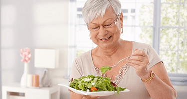 a woman with dentures smiling and enjoying a meal