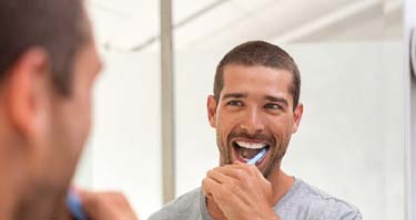 Man brushing his teeth to prevent a toothache in Guilderland