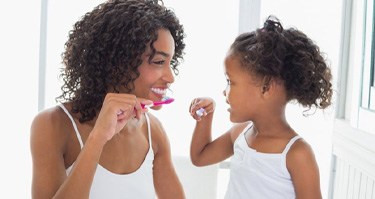 mother and daughter brushing their teeth together   