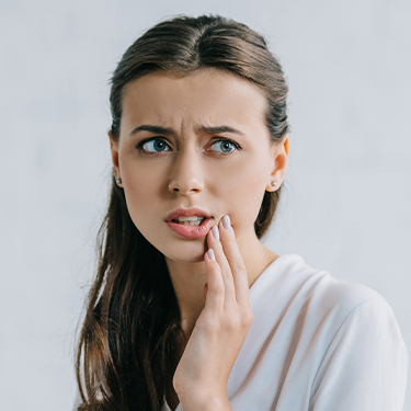 Woman in need of tooth extraction holding cheek