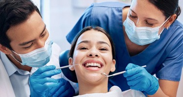 a patient smiling while her dentist checks her teeth