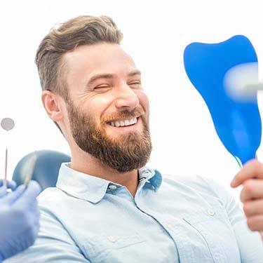 bearded man admiring his smile in a mirror 