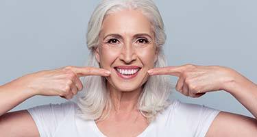 senior woman pointing to her smile 