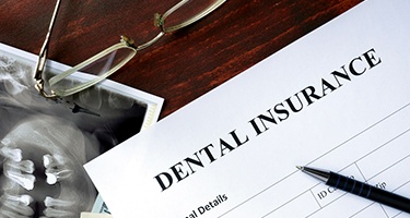 A patient looking over an insurance form with her dental team in Guilderland, NY