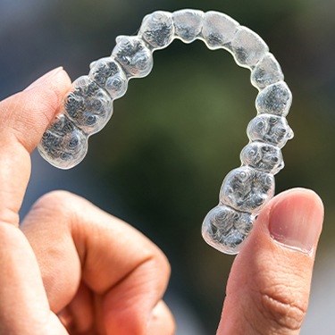 Hand holding Invisalign clear aligner