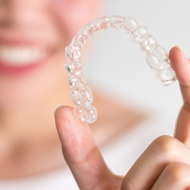 Smiling woman holding Invisalign tray