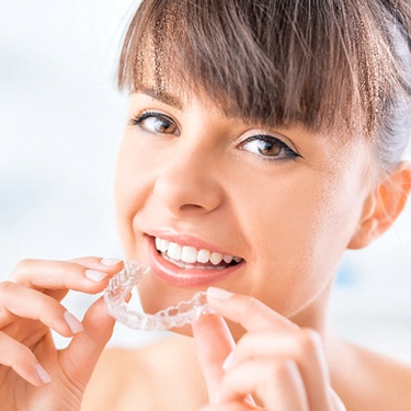 Smiling woman putting in Invisalign tray