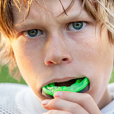 Teen placing a green athletic mouthguard