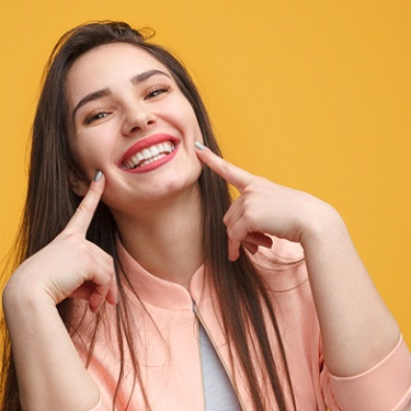 Woman pointing to her smile after teeth whitening