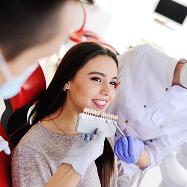 Dentist holding up veneer shades next to patient's smile