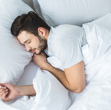 Man sleeping in bed with white sheets