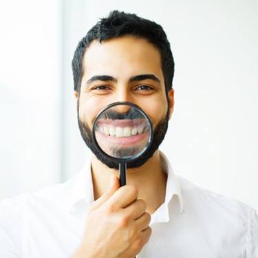 man showing off his smile with a magnifying glass 
