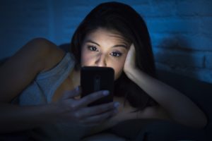 woman using her cell phone in bed late at night 