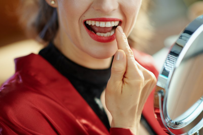 Woman pointing at smile after seeing cosmetic dentist