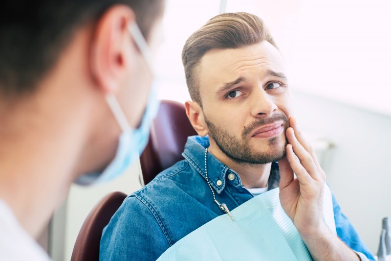 man holding cheek during emergency dental visit in Schenectady