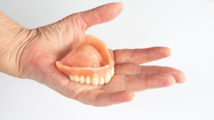 closeup of an older woman's hand holding dentures