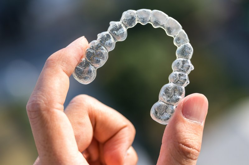 Close-up of a hand holding an Invisalign aligner