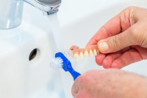Man’s hands cleaning dentures in sink