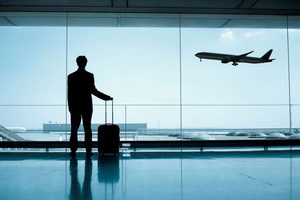 Man in airport, watching airplane take off